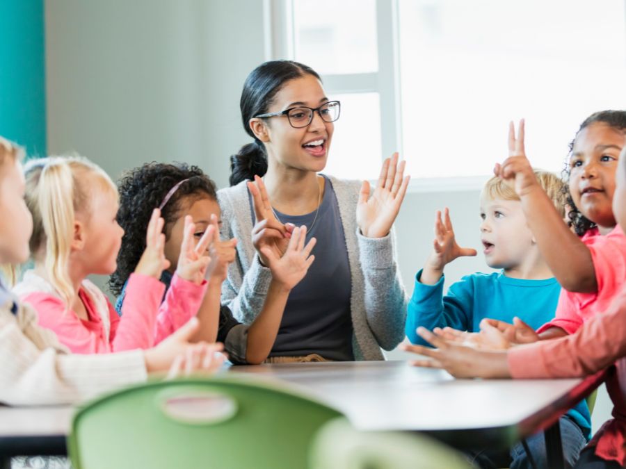 Teacher with students sitting around a table.