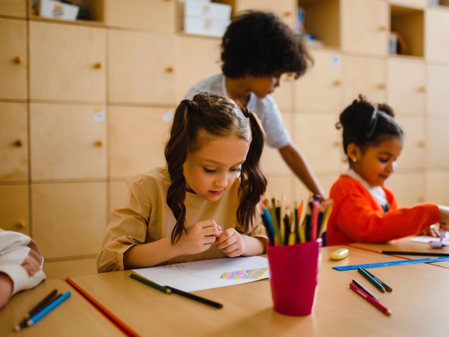 Two children coloring at a table with colored pencils.