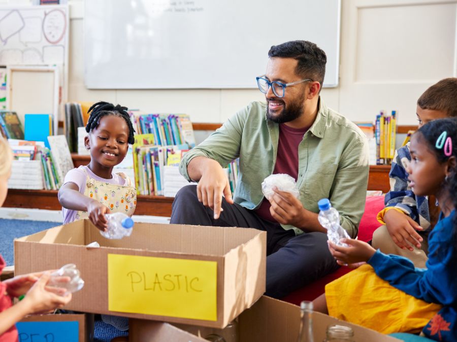 Teacher sitting with students learning about plastics.