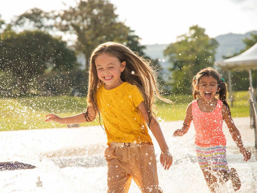Two young children running in a splash pad.