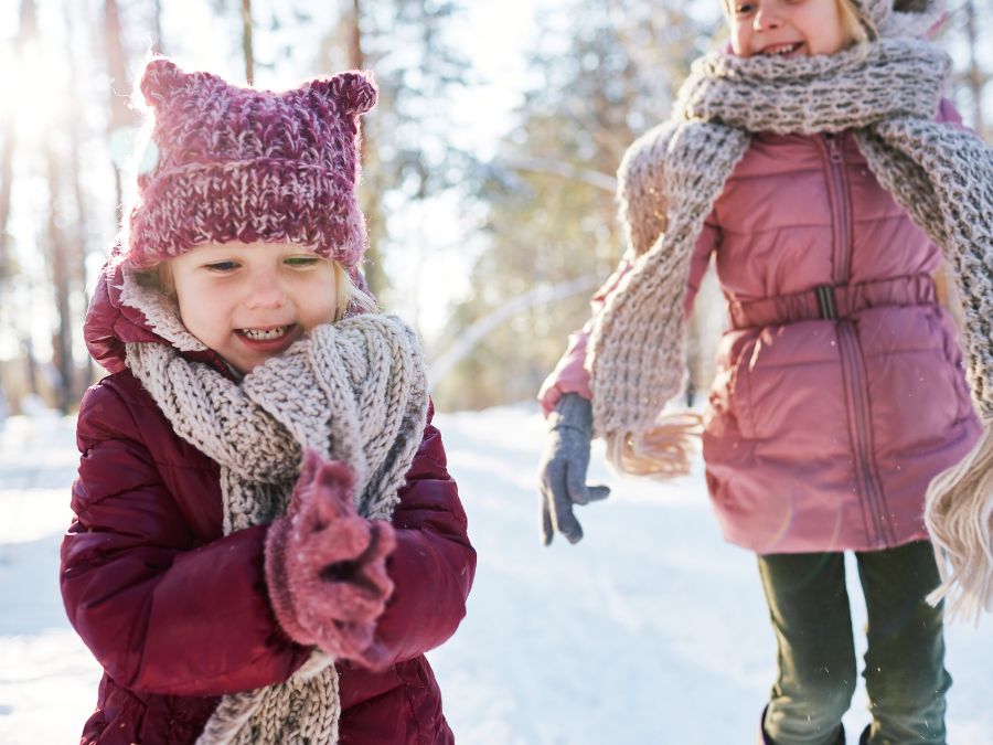 Two young children walking in the snow.
