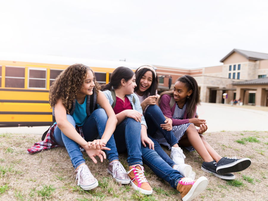 four teenagers outside of school